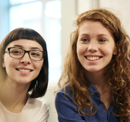 Two young women smiling while sitting indoors